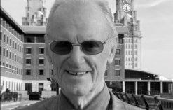 George Skelly stands in front of the camera with the Liver Buildings behind him.