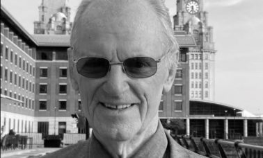 George Skelly stands in front of the camera with the Liver Buildings behind him.