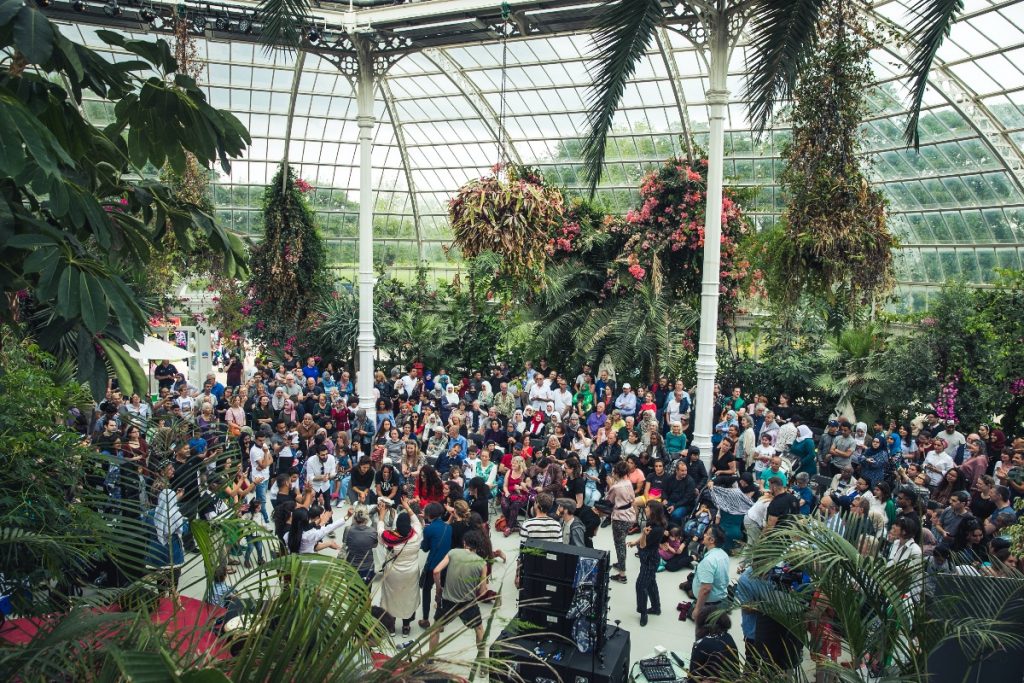 A crowd gathered and some participating in a dance inside Sefton Park's Palm House.