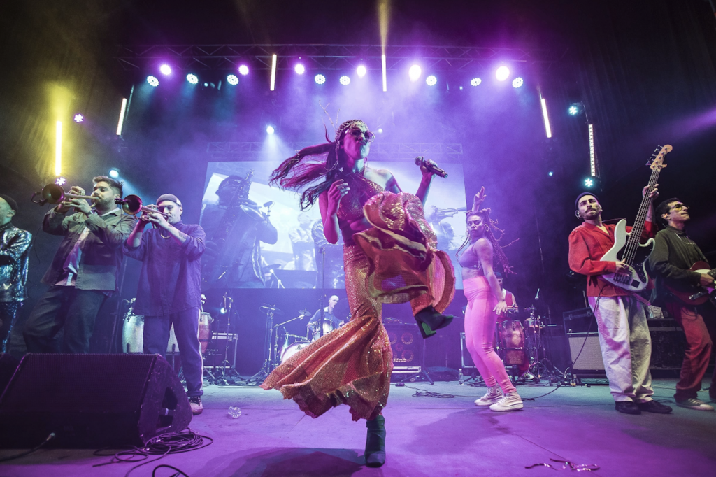A band performing on stage under purple lights