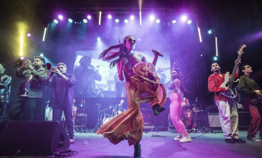 A band performing on stage under purple lights