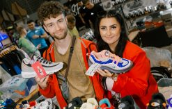 Two people holding sneakers at a sneaker convention.